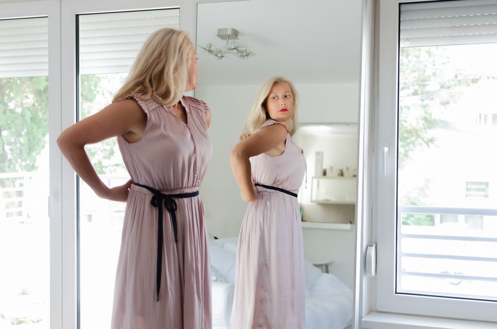 Woman looking at herself in full-length mirror